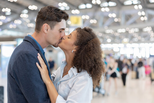A man and woman embrace and kiss each otherin the airport