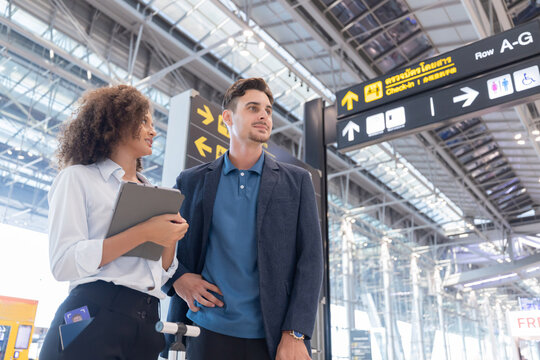 Couple checks travel details on their ticket at the airport before their flight