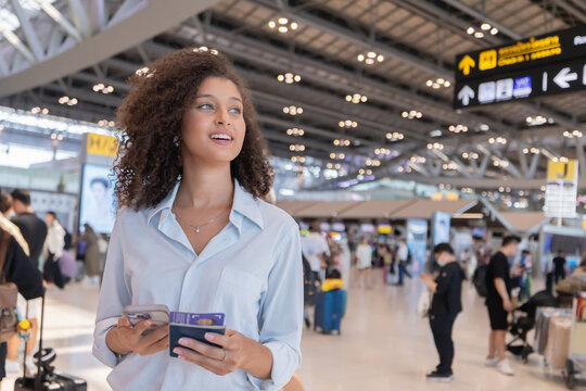 Woman talks on phone and holds passport standing at the airport terminal