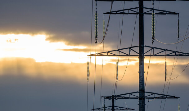 Power lines stand tall against a golden sky