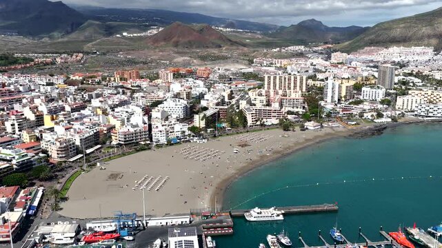 Aerial View of Playa de las Americas and Los Cristianos; Sailboats Anchored in Turquoise Bay with people swimming at the beach