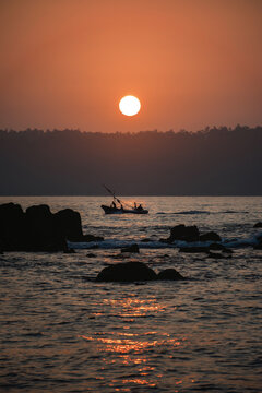 Sunset at Sea With Fishermen in a Boat Near Rocky Shore on a Calm Evening