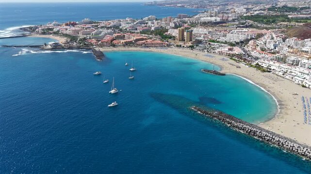 Aerial View of Playa de las Americas and Los Cristianos; Sailboats Anchored in Turquoise Bay with people swimming at the beach