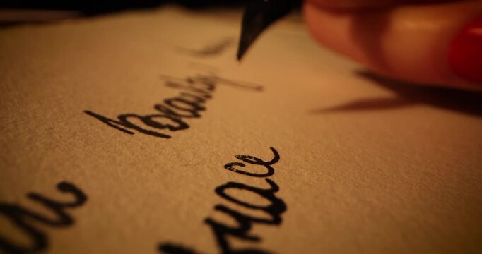 writing letter with vintage quill pen and ink on old parchment paper by candlelight. close up