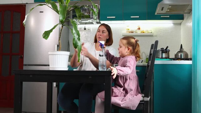 Mother and child caring for green indoor plants together, watering and observing leaves, family lifestyle, eco habits and home comfort. Mid shot
