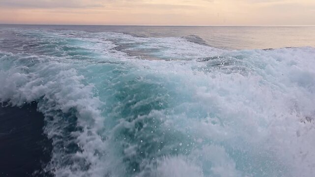 Speedboat wake splashing on the sea at sunset