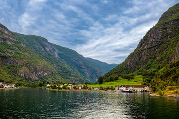 Fototapeta premium Panoramic View of Flåm Village Nestled Between Massive Mountains and Fjord