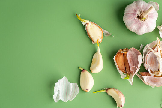fresh garlic cloves with peel on green background