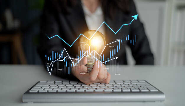 A business professional examines financial data on a keyboard, holding a light bulb. The image symbolizes innovation in financial analysis and strategy development. Scalp