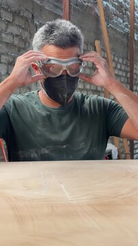 Hispanic carpenter operating an industrial thickness planer machine in a factory