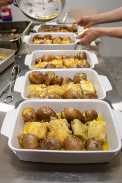 Portuguese "bacalhau &agrave; lagareiro"  with smashed potatoes and onion served on a ready-to-serve buffet tray.
