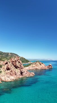Aerial view of Su Sirboni Beach, Marina di Gairo, Sardinia, Italy. Turquoise sea, rugged red cliffs and hidden coves along the wild Ogliastra coastline