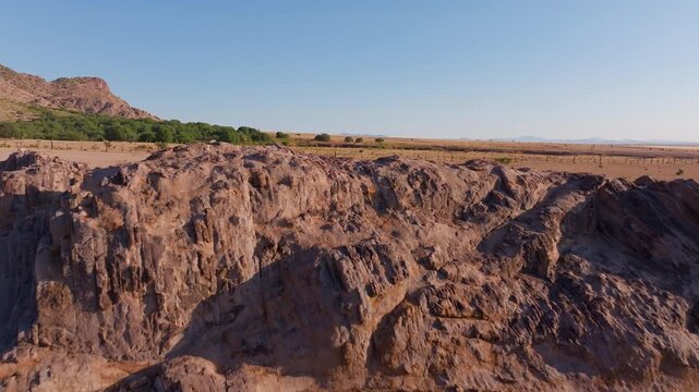 Aerial drone footage sweeps over rugged volcanic rock formations with dramatic columnar basalt structures.