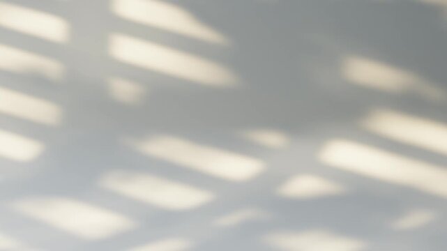 Abstract shadow from window blinds moving on a white wall creating a cinematic background, seamless loop.