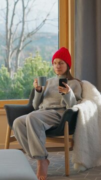 A woman using smartphone and enjoying scenic snowy mountain view.
