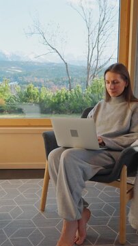 A woman using smartphone and enjoying scenic snowy mountain view.
