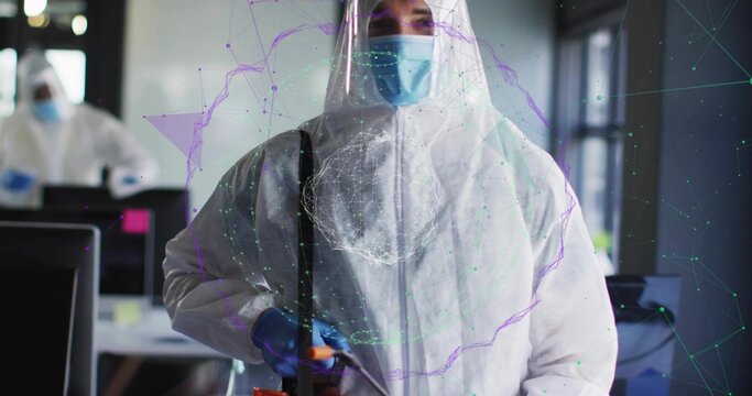 Disinfecting worker in white coverall and mask spraying office monitors with spray wand, AR overlay