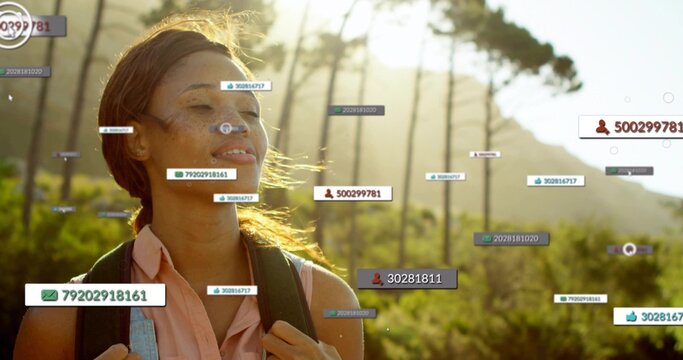 Standing woman wearing pink top, dark backpack facing sunlit trail with floating labels, copy space