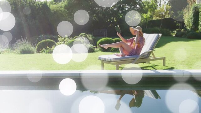 Woman raising tablet, stretching leg, tilting hat, bokeh overlaying, pool mirror tracing, leisure