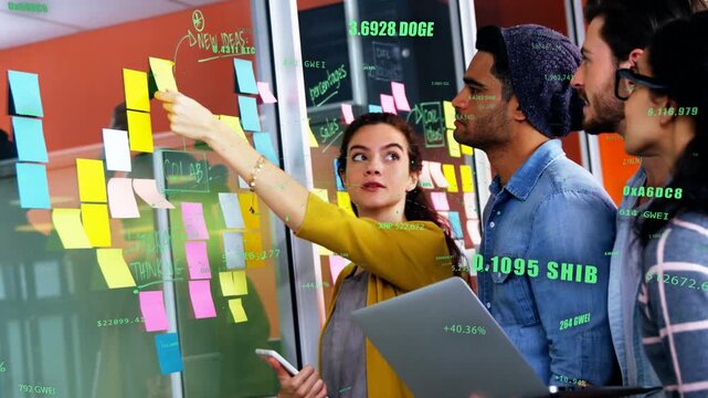 Female facilitator adding stickies on glass, revealing crypto tickers, phone laptop guiding roadmap