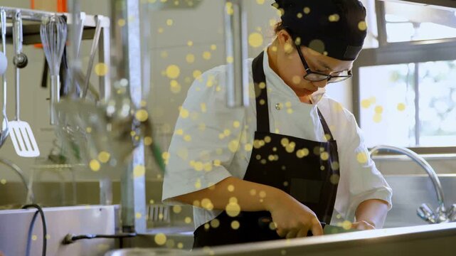Chef placing food on green board, chopping knife at prep sink, yellow bokeh overlaying foreground