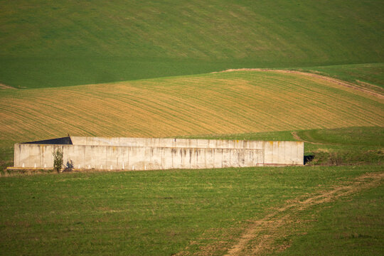 Concrete manure storage facility in rolling agricultural fields in Slovakia. Concept of farming, rural industry and human impact on natural landscape.