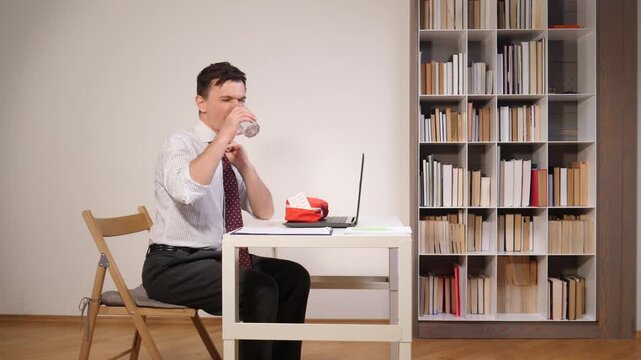Businessman holding his head suffering from a headache and needing to take medication, experiencing workplace burnout due to a heavy workload and long hours in the office