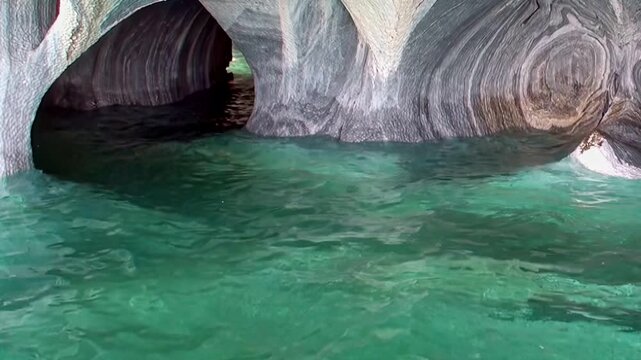Witness the stunning natural beauty of the Marble Caves in Patagonia. Crystal clear turquoise water gently laps against intricately sculpted marble formations, revealing a majestic natural wonder.