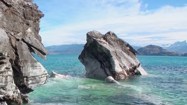 Marvel at the vibrant turquoise hues surrounding the majestic Marble Caves of Patagonia. Natural rock formations stand tall in the pristine water, basking in daylight.