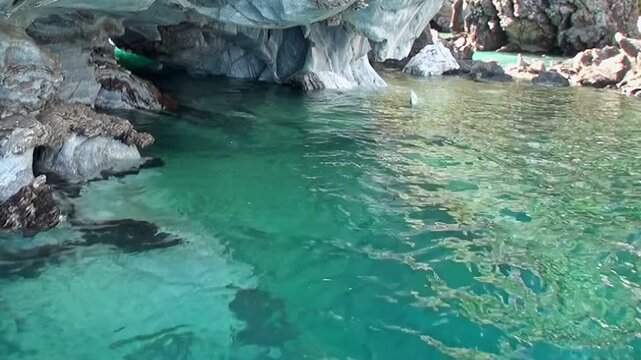 Marvel at vibrant turquoise waters and sculpted rock formations within General Carrera Lake Marble Caves. Sunlight dances across Patagonian wonder, revealing its stunning beauty on bright day.