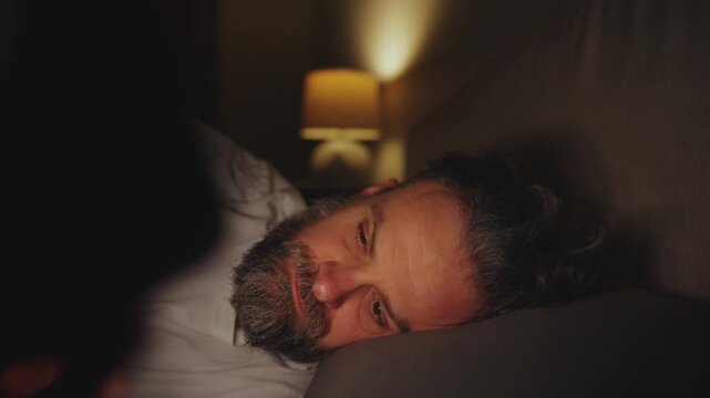 A man lying in bed using smartphone late at night. 
