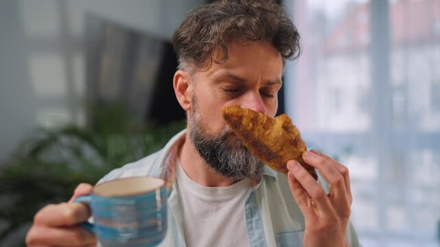 A man enjoying a fresh croissant and coffee for breakfast
