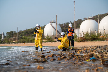 Fototapeta premium Environmental scientists in protective hazmat suits collecting water samples for pollution analysis and ecological research at an industrial site.