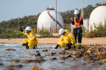 Fototapeta premium Environmental scientists in protective hazmat suits collecting water samples for pollution analysis and ecological research at an industrial site.