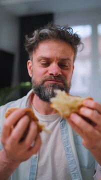 A man enjoying a fresh croissant for breakfast. Vertical