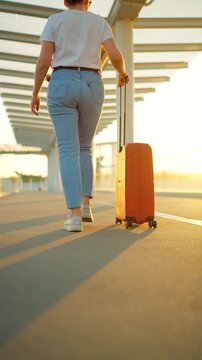 Woman confidently pulling a suitcase in an airport terminal. Back view