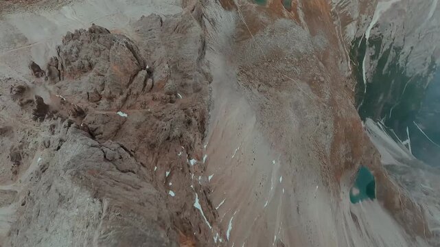 FPV drone flying along the surface of mountain cliffs of Cristallo mountain.