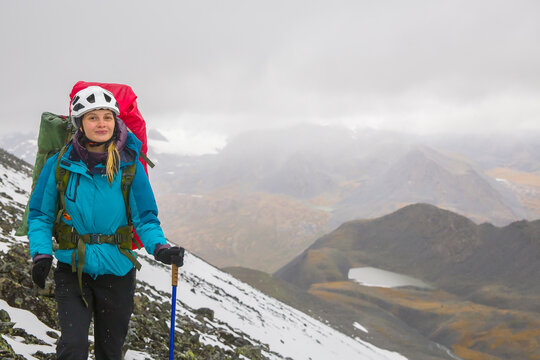 Young female climber against the backdrop of snow-capped mountains.