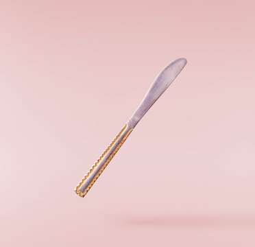 Levitating metal knife  isolated on a pink background. Minimalist zero gravity tableware concept.