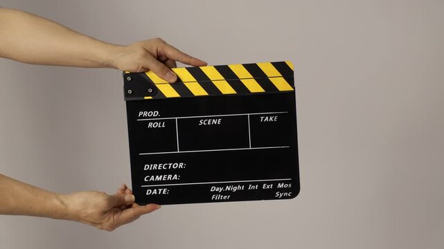 Hand is holding clapper board on white background.