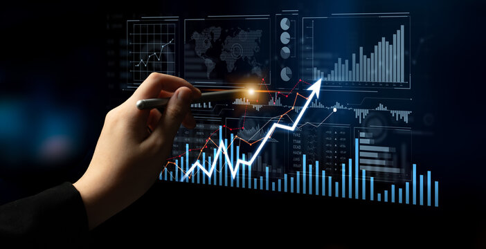 A hand is holding a pen while analyzing digital financial data displayed on a screen, showcasing graphs and growth indicators within a professional business context. Scalp