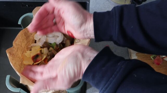Stockholm, Sweden A cook in a residential kitchen cleans up vegetable cuttings into a compostable brown paper bag. 