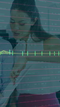 Vertical video: Woman leaning and tracing doc held by peer, reviewing in biz, green pulse overlay