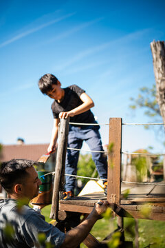 Father and son painting wooden treehouse together