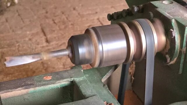 Lathe machine spindle rotating at high speed with a rubber drive belt in a traditional woodworking workshop High Quality Footage