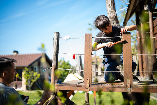 Father and son building wooden treehouse together