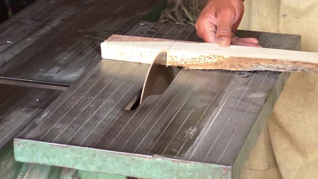 Carpenter hands cutting raw timber on a circular table saw in a rustic workshop environment High Quality Footage
