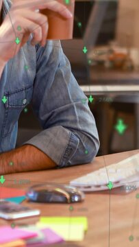 Vertical video: Male worker reaching for cup, sipping while green finance data floating around cup