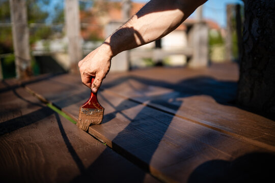 Hand painting wooden deck floor, applying protective stain