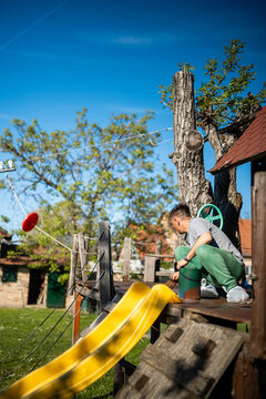 Man painting backyard playground slide on sunny day
